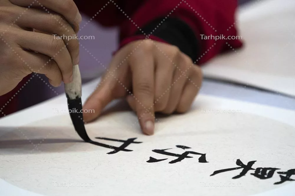 عکس زنی ژاپنی در حال نوشتن نام چارلز با قلم موی سنتی