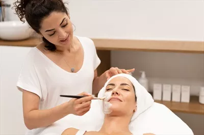 عکس متخصص زیبایی در حال اعمال ماسک صورت بر روی مشتری