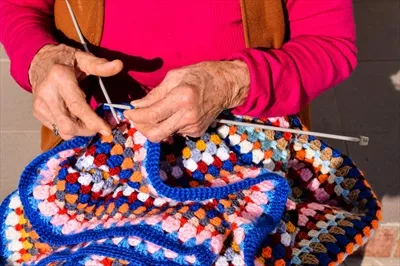 عکس زنی که با دقت و عشق در حال بافتن پارچه ای زیبا است