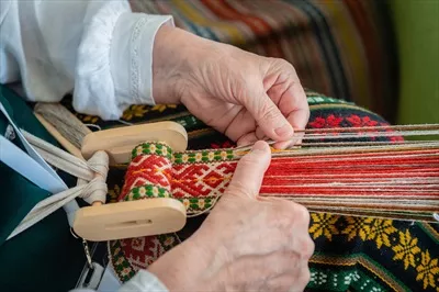 عکس زنی در حال کار بر روی دار قالی، نمایانگر هنر سنتی و قومی بالتیک