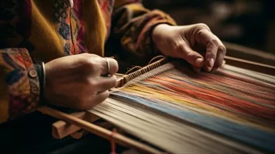 عکس دست های سالمندان در حال بافت پارچه های ابریشمی رنگارنگ بر روی دار قالی