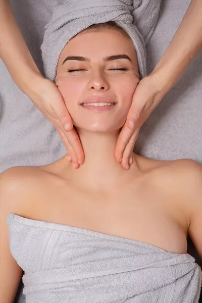 عکس زنی جوان و زیبا در حال دریافت ماساژ صورت در سالن زیبایی