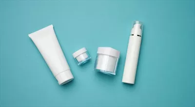 عکس بطری شیشه ای و لوله های پلاستیکی خالی برای محصولات آرایشی بر روی پس زمینه آبی