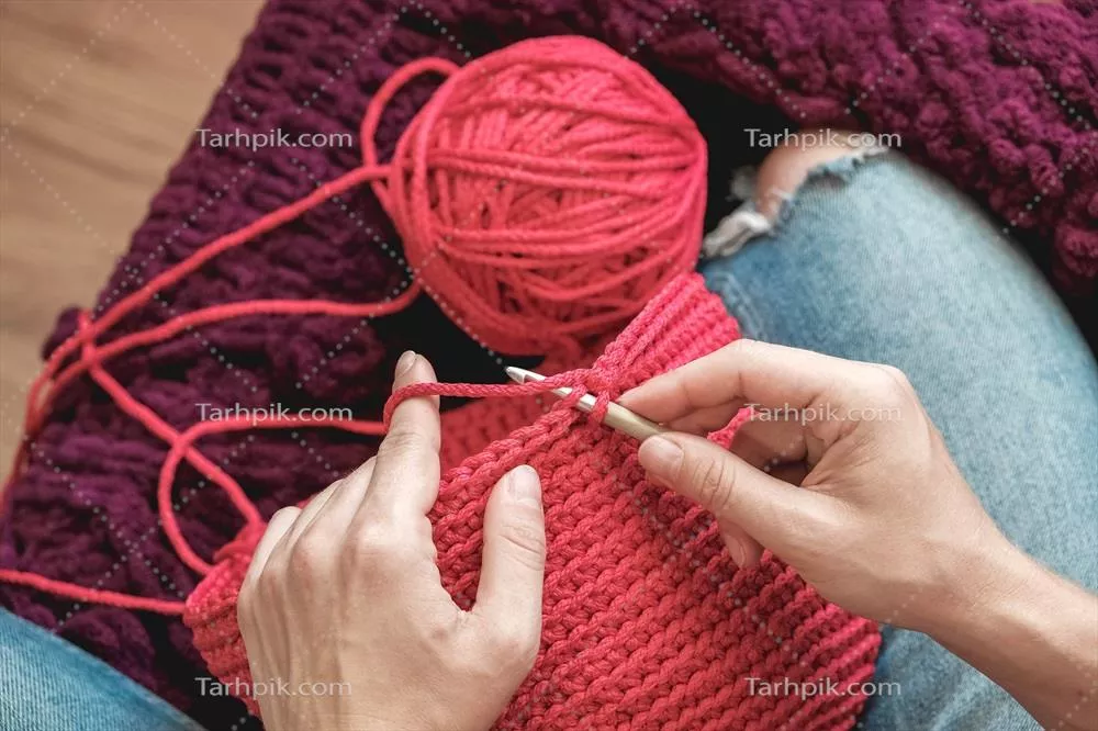 عکس زنی در یک محیط دلنشین خانگی در حال بافتنی با نخ صورتی