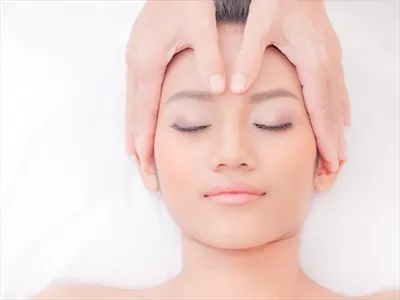 عکس زنی زیبا از آسیای شرقی در حال آرامش در یک مرکز اسپا با ماساژ صورت