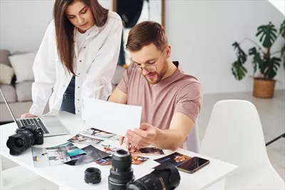 عکس دو عکاس در لباس های غیررسمی در حال کار در محیط داخلی در روز