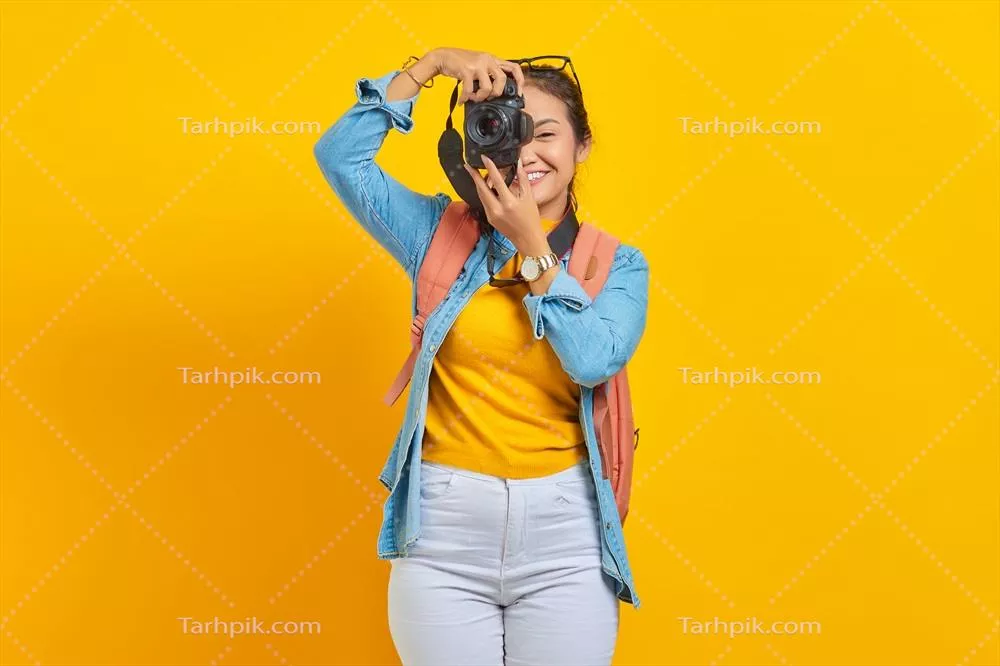 عکس پرتره ای از زن جوان آسیایی شاد با کوله پشتی در پس زمینه زرد