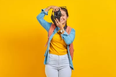 عکس پرتره ای از زن جوان آسیایی شاد با کوله پشتی در پس زمینه زرد