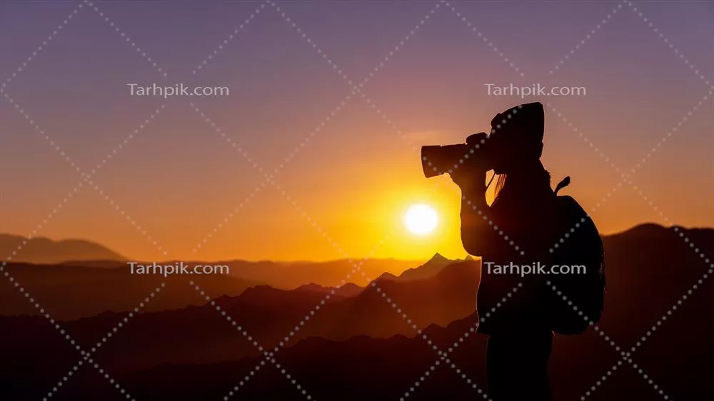 عکس عکاسی از یک زن جوان هیپی در غروب آفتاب بر فراز کوه با پس زمینه طبیعی