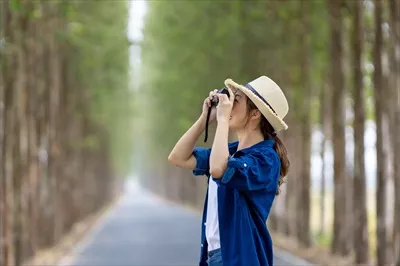 عکس زن گردشگر آسیایی در حال عکاسی با دوربین حرفه ای در پارک ملی