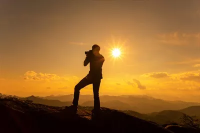 عکس تصویری زیبا از عکاس در حال ثبت لحظه غروب در کوهستان