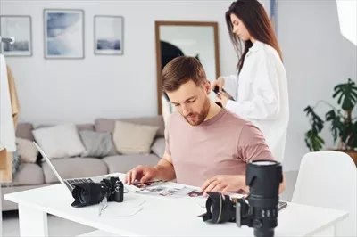 عکس دو عکاس در لباس های غیررسمی در حال کار در محیط داخلی در روز