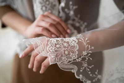 عکس نزدیک نمایی از تور عروسی با الگوی گلدوزی شده بر روی دست