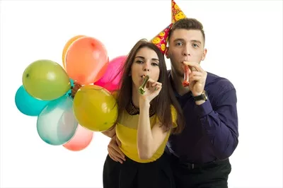 عکس جشن تولد شاد یک زوج جوان با کلاه های شاخ دار و بادکنک های رنگی