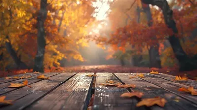 عکس میز چوبی زیبا در پس زمینه ای از پاییز با برگ های در حال سقوط