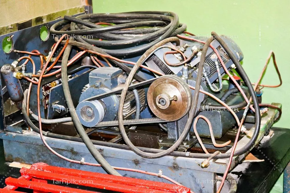 عکس موتور الکتریکی قدیمی با لوله ها و شلنگ ها در یک کارخانه صنعتی