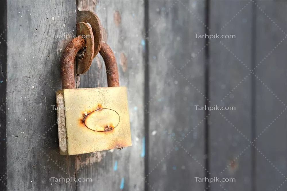 عکس قفل زنگ زده بر روی درب چوبی: نمادی از گذر زمان و فرسودگی