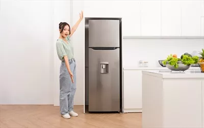 عکس زنی آسیایی در کنار یخچال در آشپزخانه، لحظه ای از زندگی روزمره