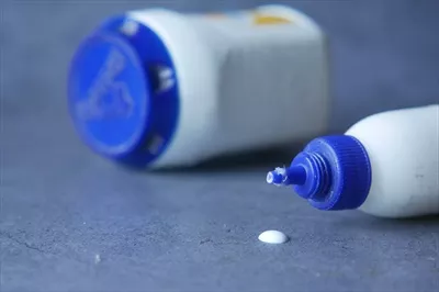 عکس بطری چسبی که بر روی زمینه سیاه ریخته شده است