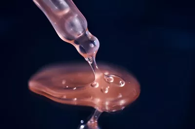 عکس بطری حاوی سرم صورتی بر روی پس زمینه آبی - نمایی جذاب و هنری