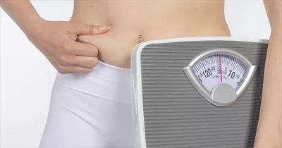 عکس مدل زن با ترازوی دستی و نوار اندازه گیری در پس زمینه سفید