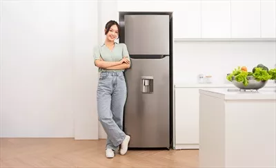 عکس زنی آسیایی در کنار یخچال در آشپزخانه، لحظه ای از زندگی روزمره