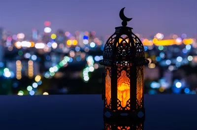 عکس چراغی با نماد ماه در بالای آن، در پس زمینه شب شهر برای جشن مسلمانان در ماه مبارک رمضان