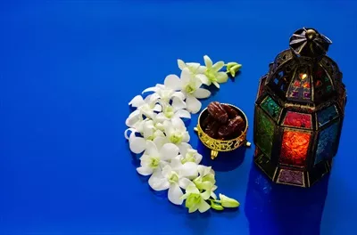 عکس چراغ های زیبا بر روی زمینه آبی با خرما و گل ارکیده برای جشن رمضان