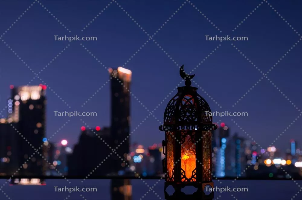 عکس چراغی با نماد ماه در بالای آن، در پس زمینه شب شهر برای جشن رمضان