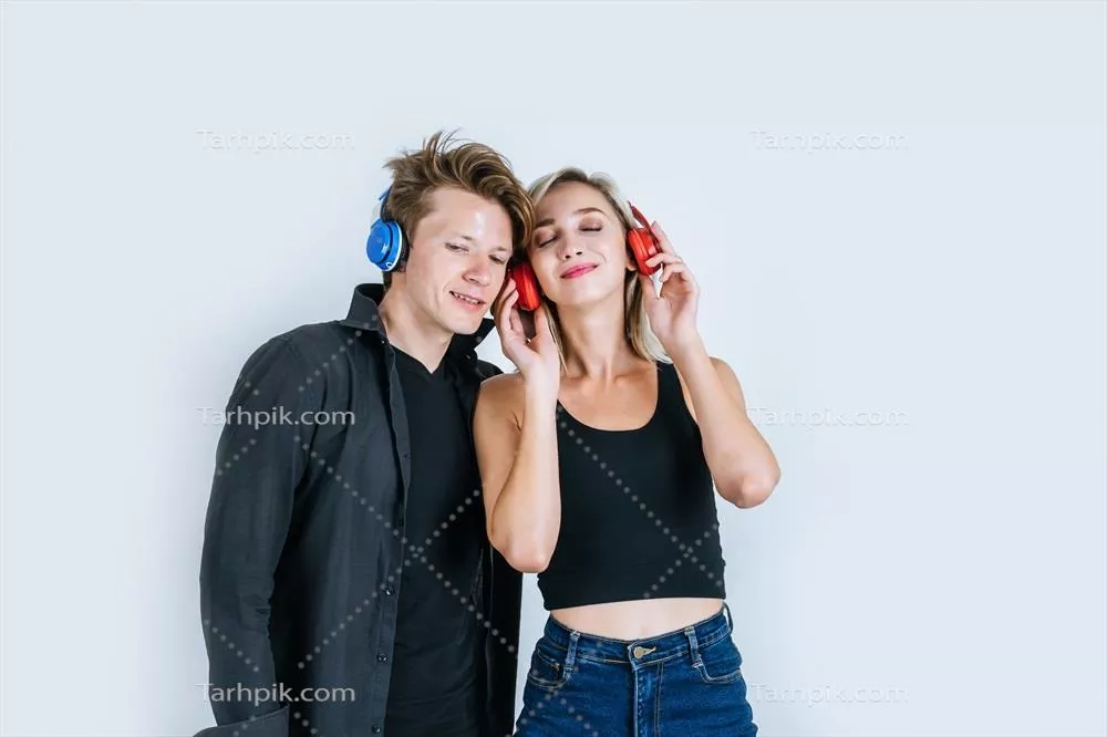 عکس زوج جوان شاد در استودیو، در حال گوش دادن به موسیقی با هدفون