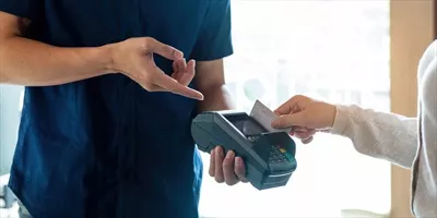 عکس تصویری نزدیک از دست مشتری که با کارت اعتباری پرداخت می کند