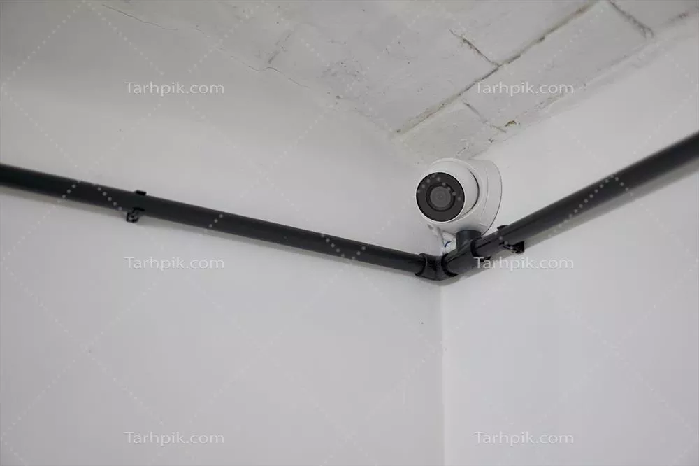 عکس دوربین مداربسته گرد سفید رنگ نصب شده در گوشه دیوار سفید