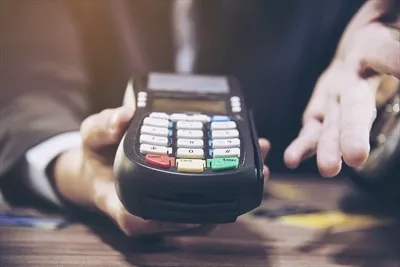 عکس استفاده از دستگاه کارتخوان توسط یک فروشنده برای پرداخت مشتری