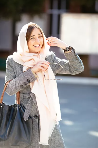 دختر جوانی که در خیابان کت پوشیده است و در حال قدم زدن است
