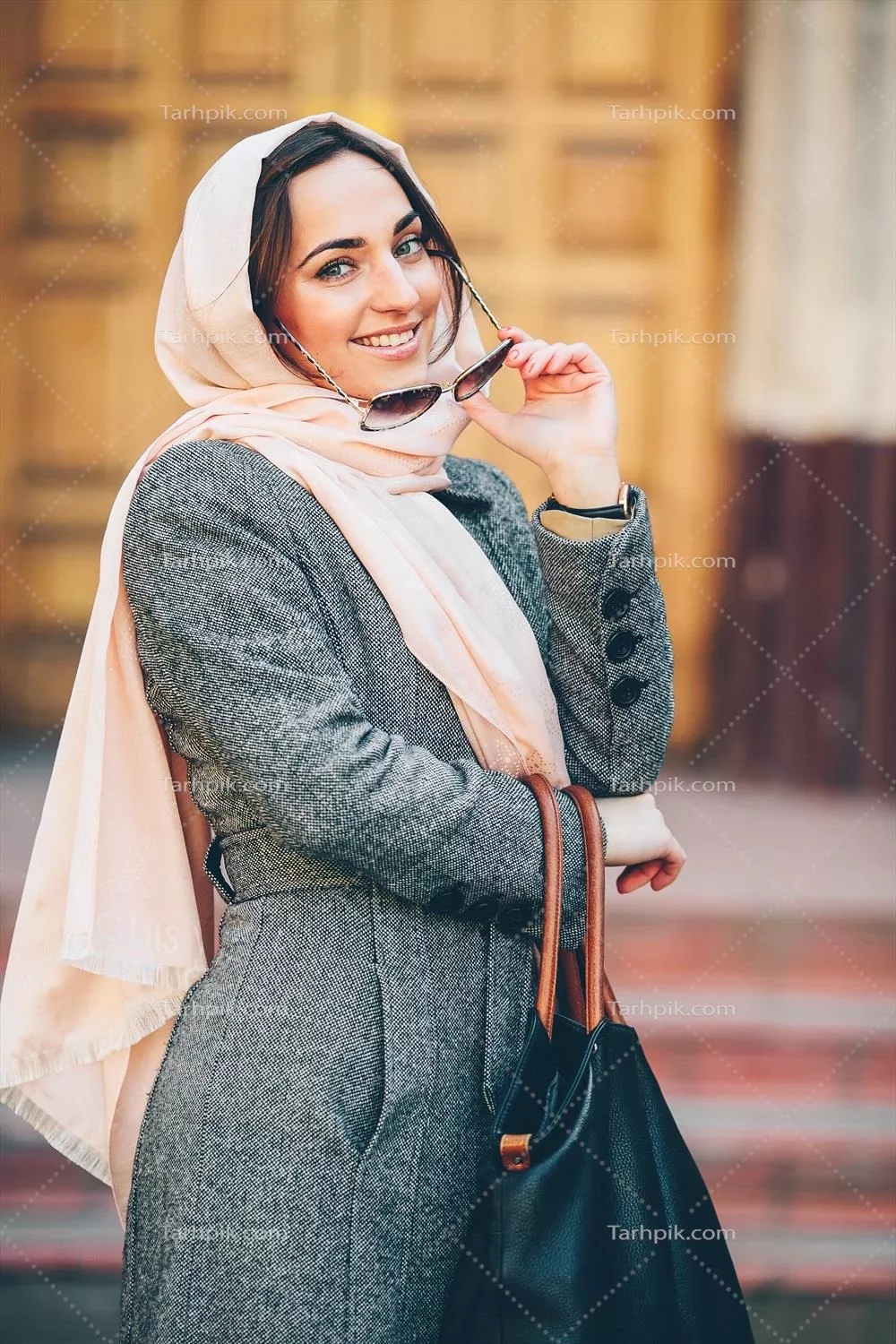 دختر با پالتو در حال مدلینگ در پس زمینه یک ساختمان جذاب