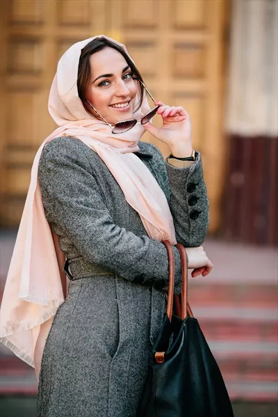 دختر در کت با پسزمینهای از ساختمان در حال ژست گرفتن