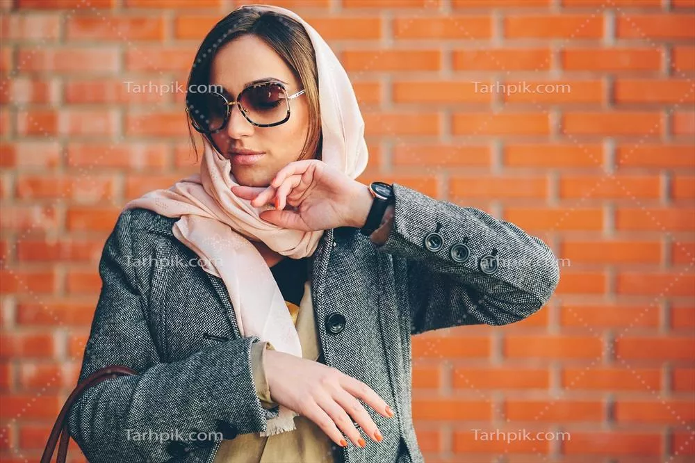 دختری که در حال ژست گرفتن در برابر دیوار آجری قرمز است