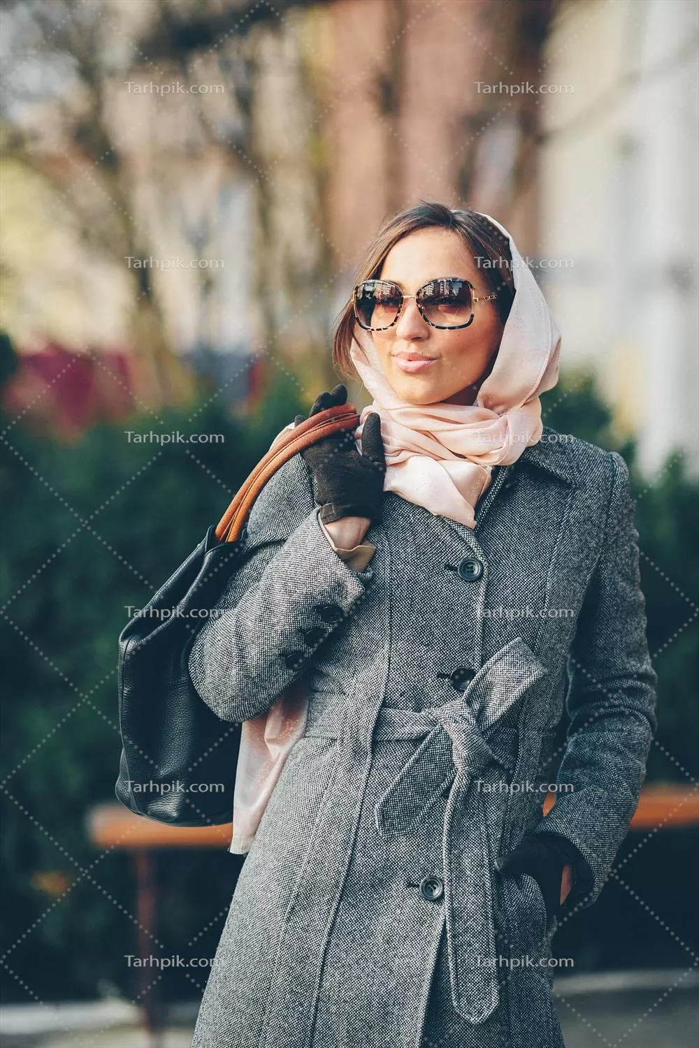 دختر جوان و زیبا با لبخند در پارک در حال ژست گرفتن