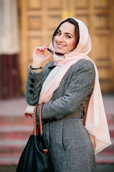 دختر خوشتیپ در حال مدلینگ با کاپشن بر روی پسزمینه ساختمان