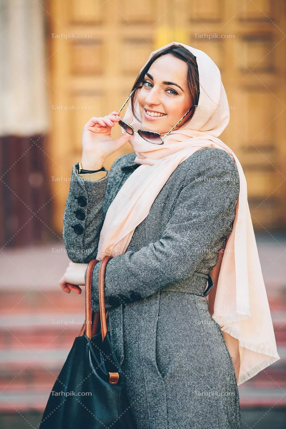 دختر در حالتی خاص با کت در پس‌زمینه ساختمان‌های شهری