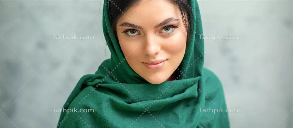 پرترهای از زن جوان قفقازی زیبا با آرایش و روسری سبز روی پسزمینه خاکستری