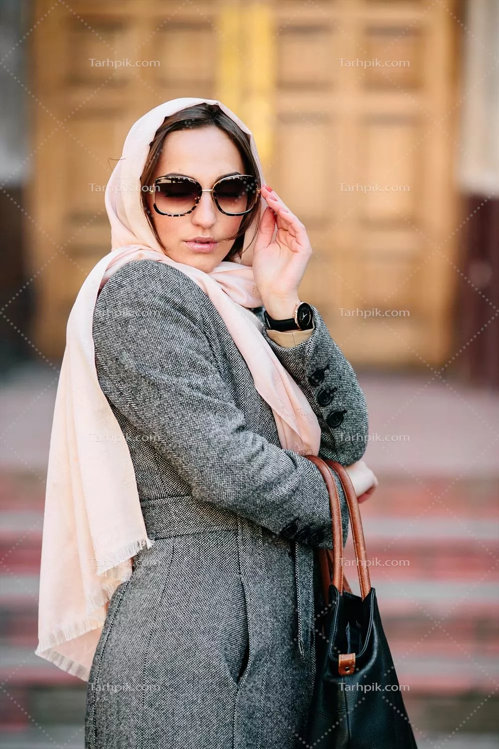 دختری با پالتو در پیش زمینه یک ساختمان زیبا ایستاده است