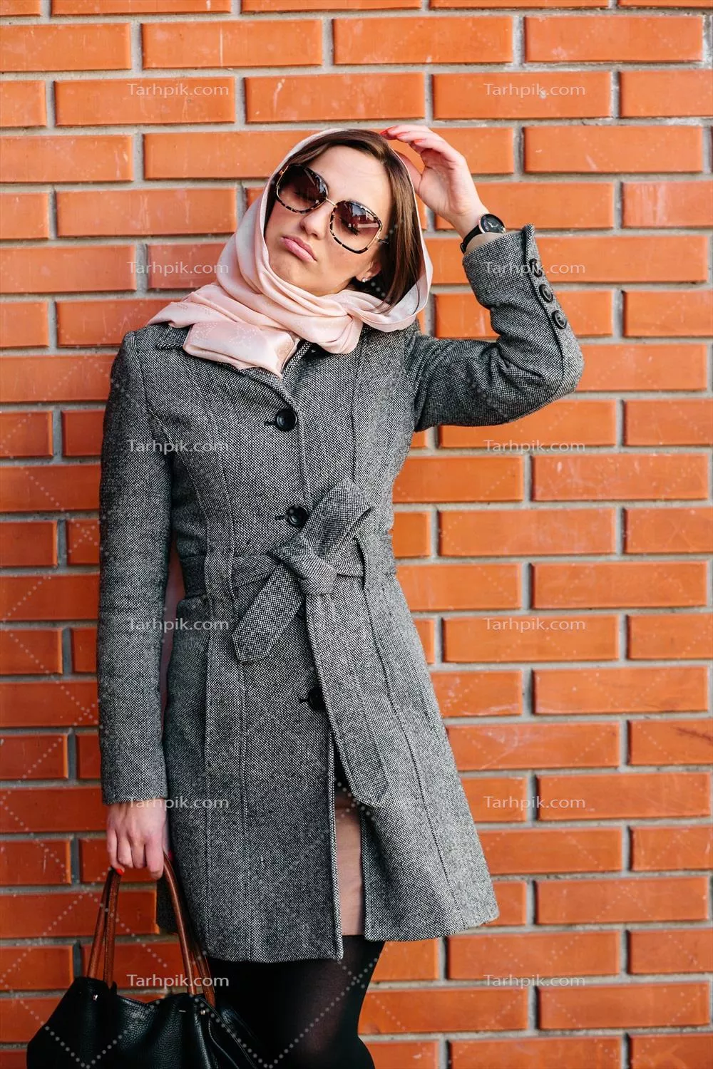 دختر در حال ژست گرفتن در پسزمینه دیوار آجری قرمز