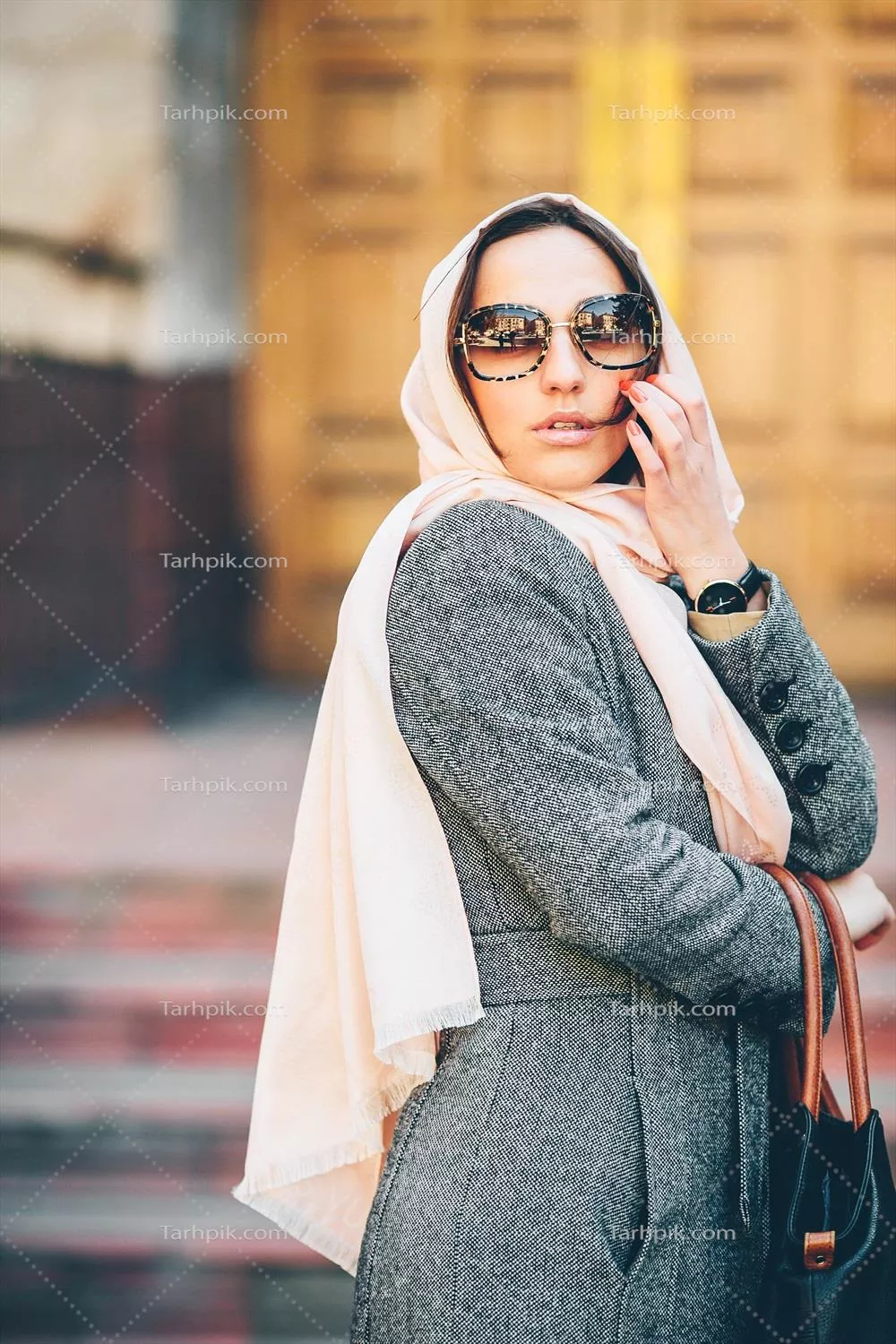 دختری با پالتو در حال ژست گرفتن در پس‌زمینه یک ساختمان زیبا