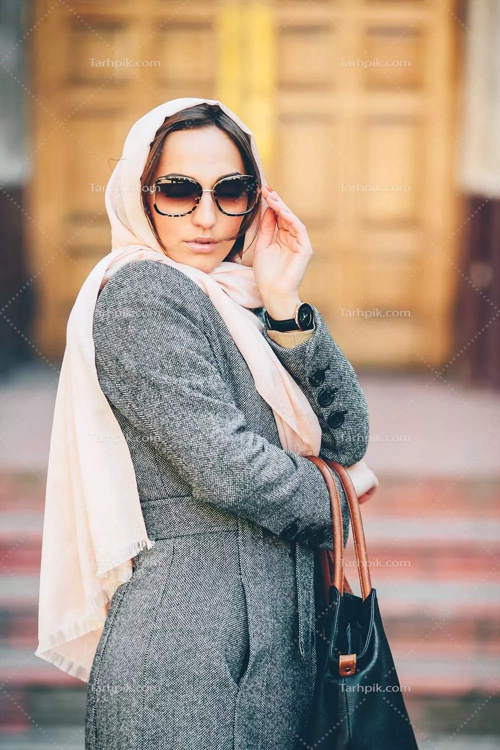 عکس یک دختر در حال ژست گرفتن با کت در پسزمینه یک ساختمان