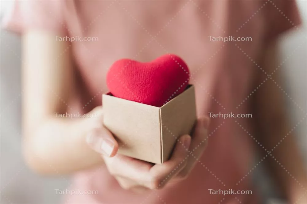 زن با دست در دست داشتن جعبه هدیه و قلب قرمز به مناسبت روز جهانی سلامت روان و روز جهانی قلب