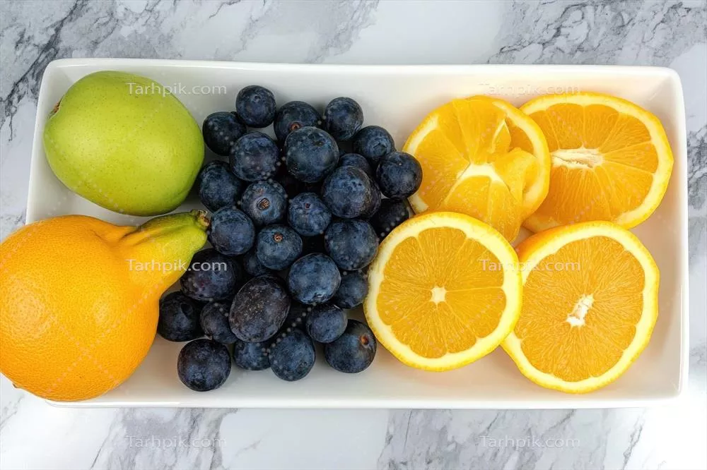 سبک زندگی سالم با میوههای تازه شامل سیب، توتهای آبی و برشهای پرتقال بر روی بشقاب