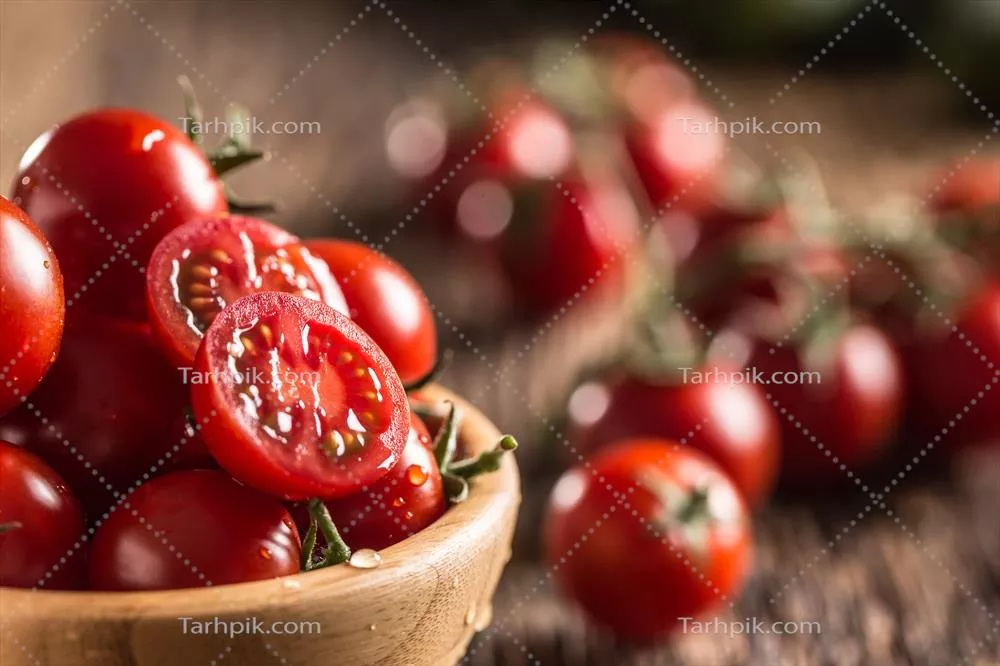 گوجه‌فرنگی‌های تازه در کاسه چوبی روی میز قدیمی بلوطی