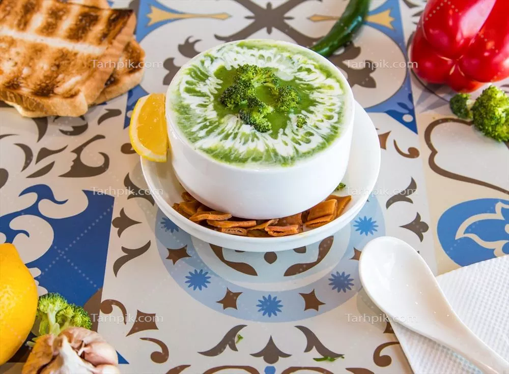 سوپ کلم بروکلی با بیسکویت لیمویی و فلفل دلمه ای بر روی میز