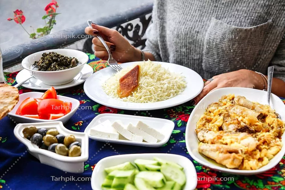 شخصی در حال نشستن در کنار میز با بشقابهای غذایی خوشمزه
